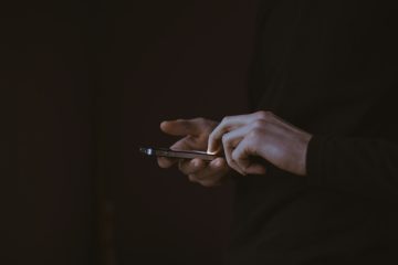 Silhouette of a person looking at a glowing smartphone screen in the dark