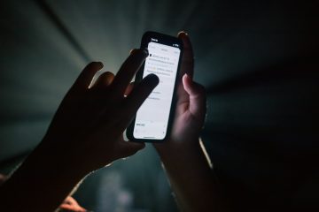 Close-up of a hand holding a smartphone in dim light, face not visible