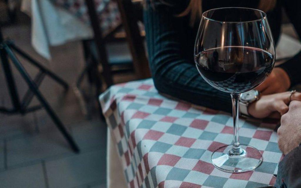 Glasses of red wine on a candlelit table set for two