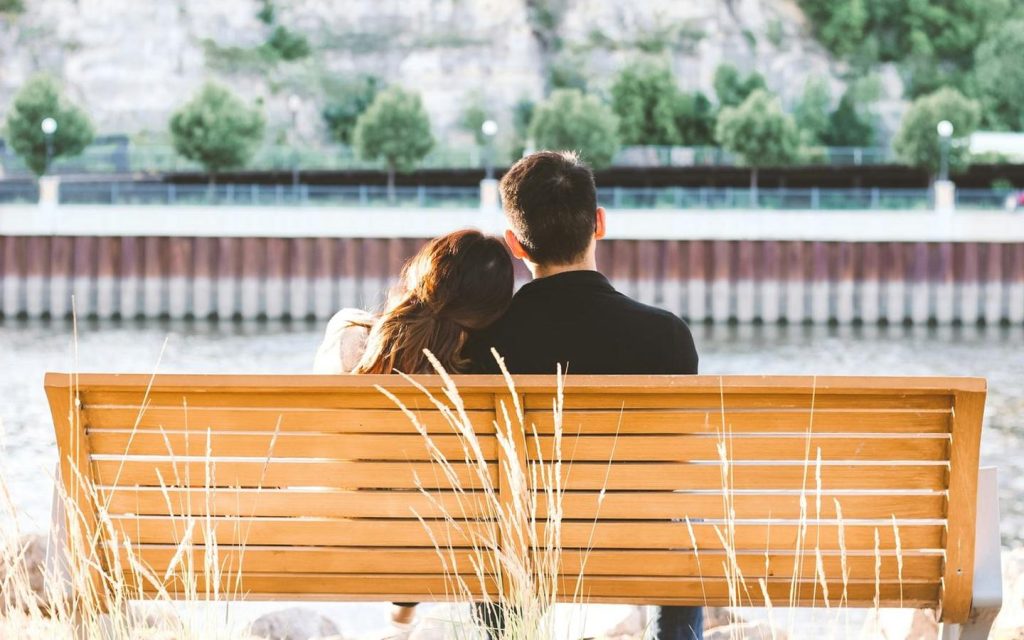 Couple sitting together on a riverside bench