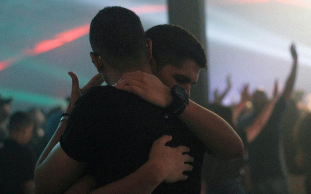 Two men embracing on a crowded dance floor