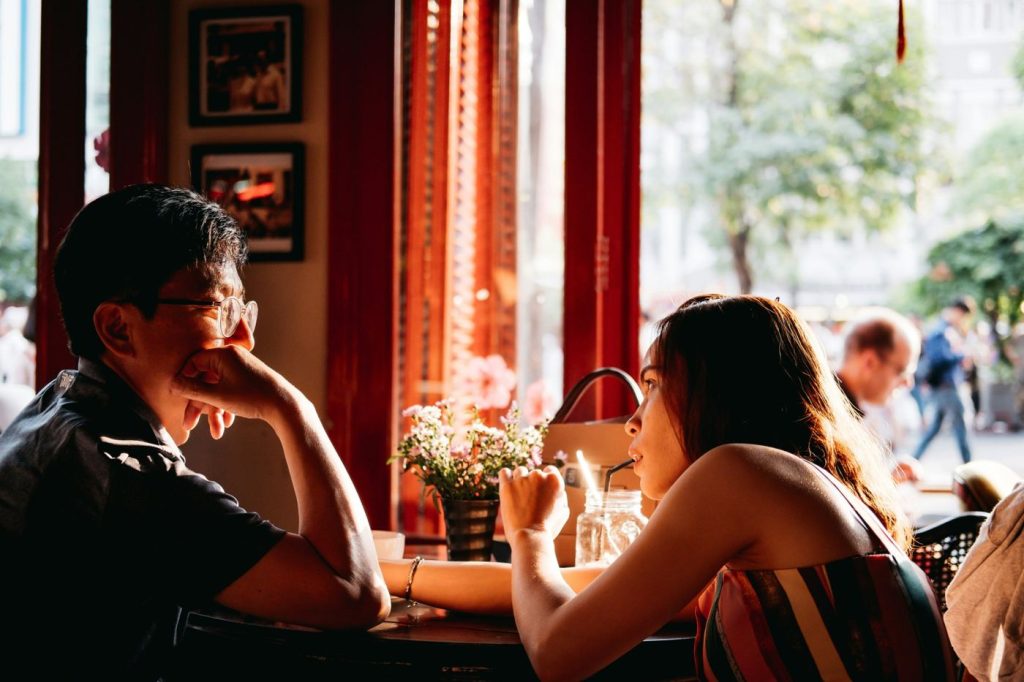 Couple talking across a table in a sunlit café