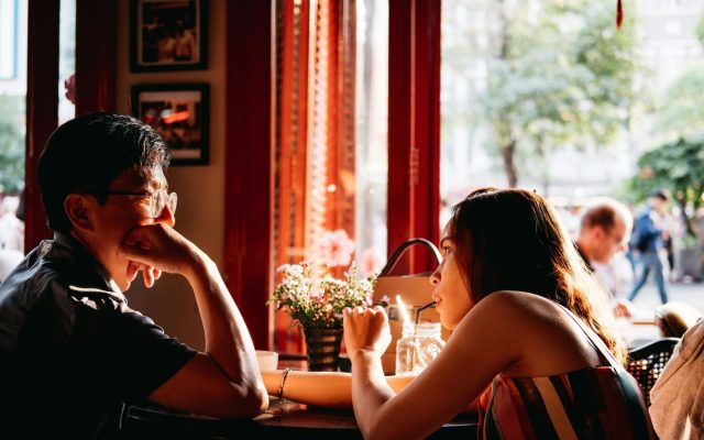 Couple talking across a table in a sunlit café