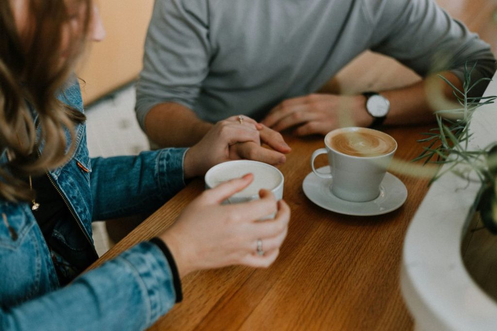 Two people holding hands over coffee cups