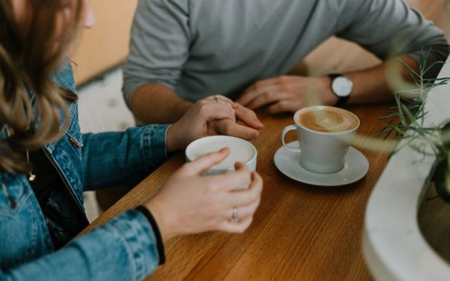 Two people holding hands over coffee cups