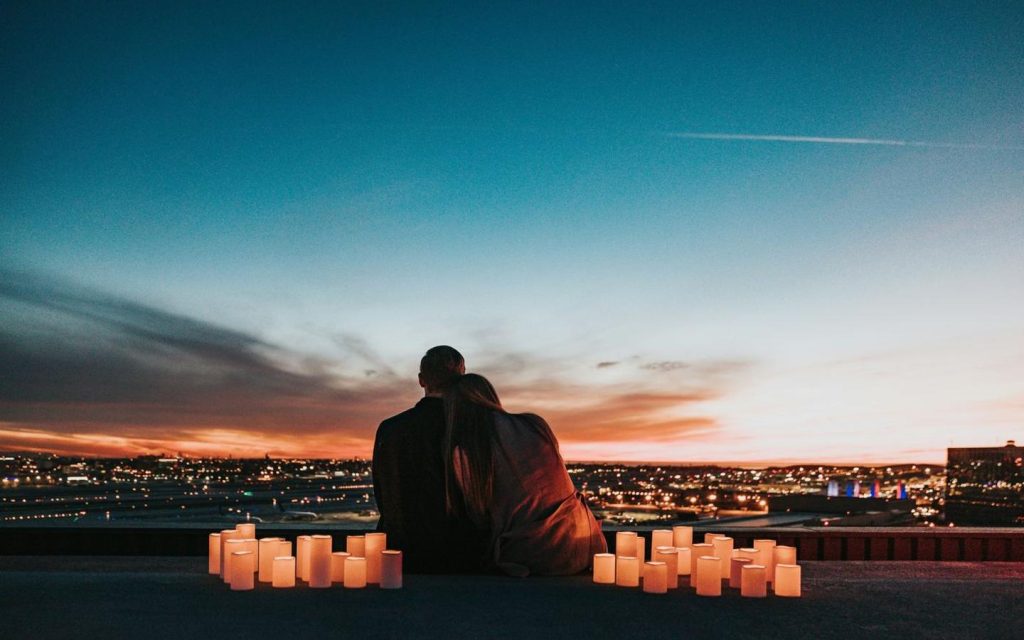 Couple on a city rooftop at dusk surrounded by candles