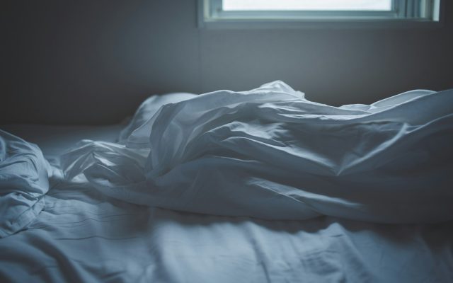 Заправленная кровать с белым одеялом у окна в мягком утреннем свете