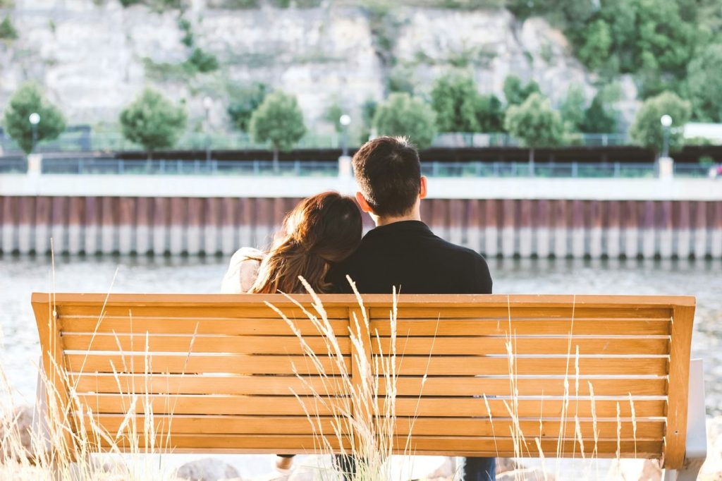 Couple sitting together on a riverside bench