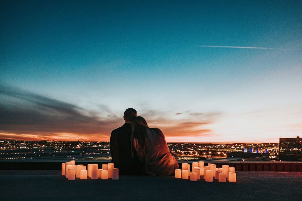 Couple on a rooftop at dusk surrounded by candles