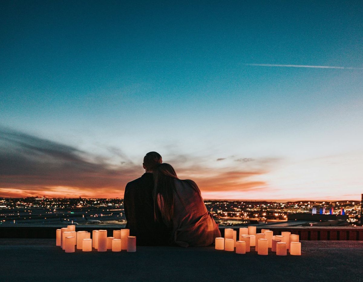 Couple on a rooftop at dusk surrounded by candles